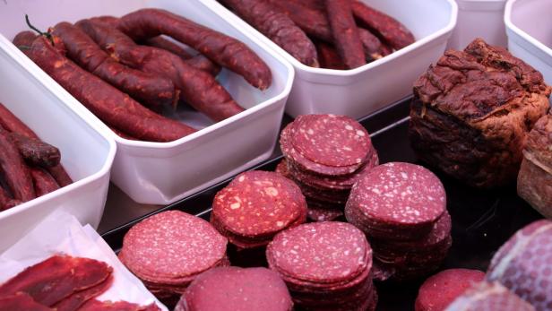 Verschiedene Wurstsorten, darunter Salami und geräucherte Würste, werden zum Verkauf angeboten.
