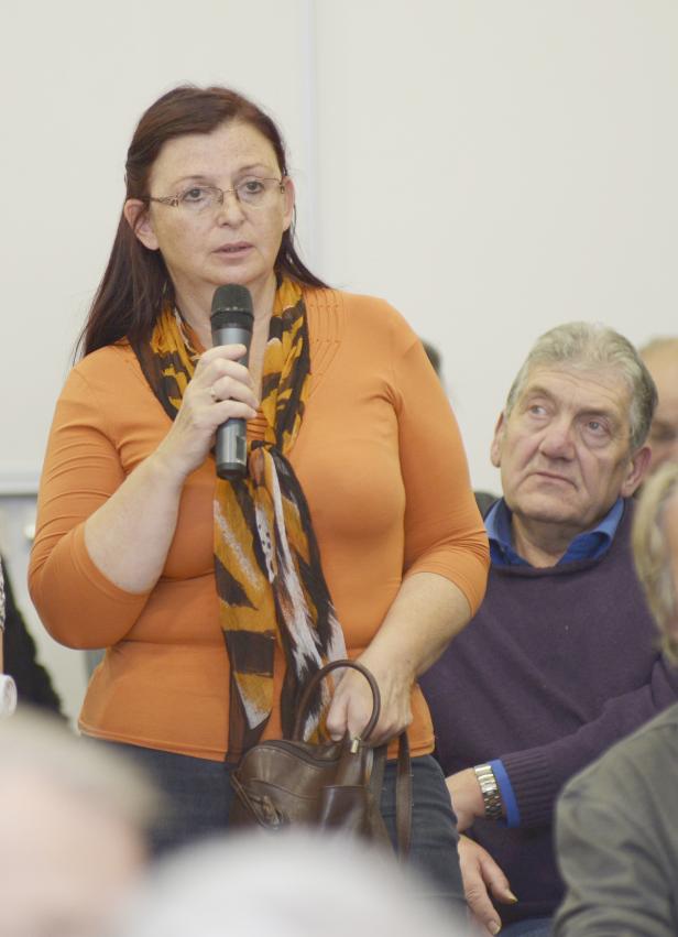 Eine Frau spricht bei einer Versammlung in ein Mikrofon.