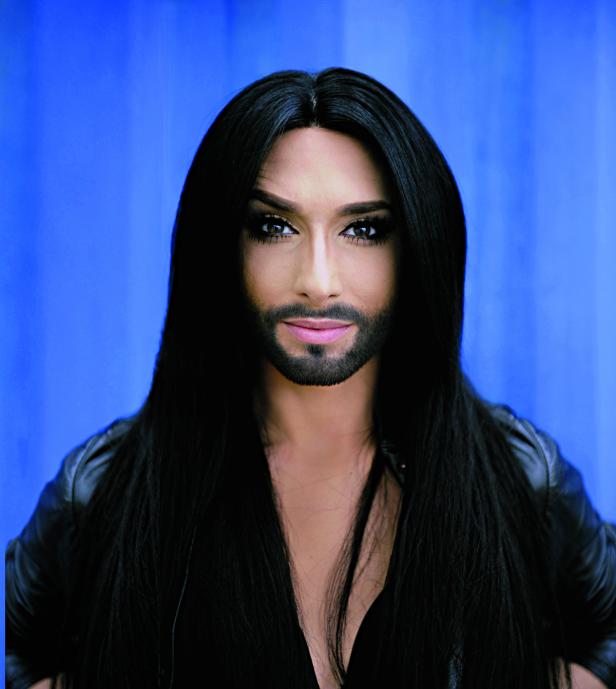 Porträt von Conchita Wurst vor einem blauen Hintergrund.