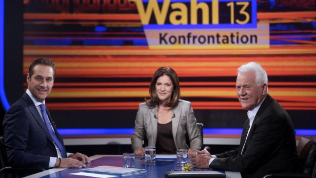 Drei Personen sitzen an einem Tisch vor dem Hintergrund einer „Wahl 13“-Konfrontation.