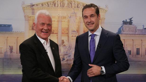Heinz Fischer und ein weiterer Mann geben sich vor dem Hintergrund des Parlaments die Hand.