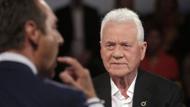 Ein Mann mit weißem Haar im Gespräch mit einer anderen Person.