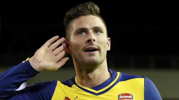 Ein Fußballspieler in einem gelb-blauen Trikot hält die Hand ans Ohr.