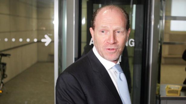 Ein Mann im Anzug steht vor einer Glastür.