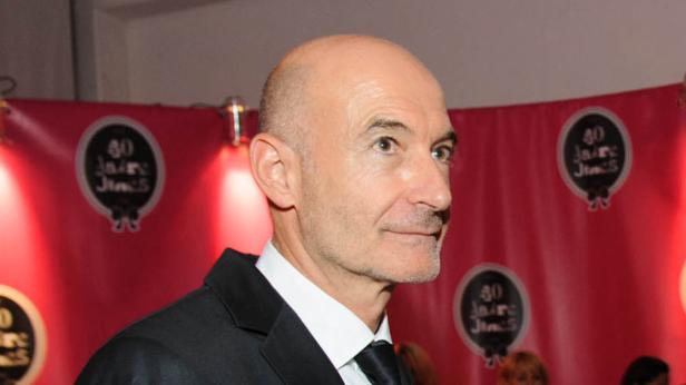 Ein Mann im Anzug vor einem roten Hintergrund mit der Aufschrift „40 Jahre JimS“.