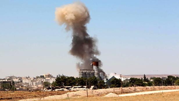 Eine Explosion erzeugt eine Rauchsäule über einem Gebäude in einer städtischen Umgebung.