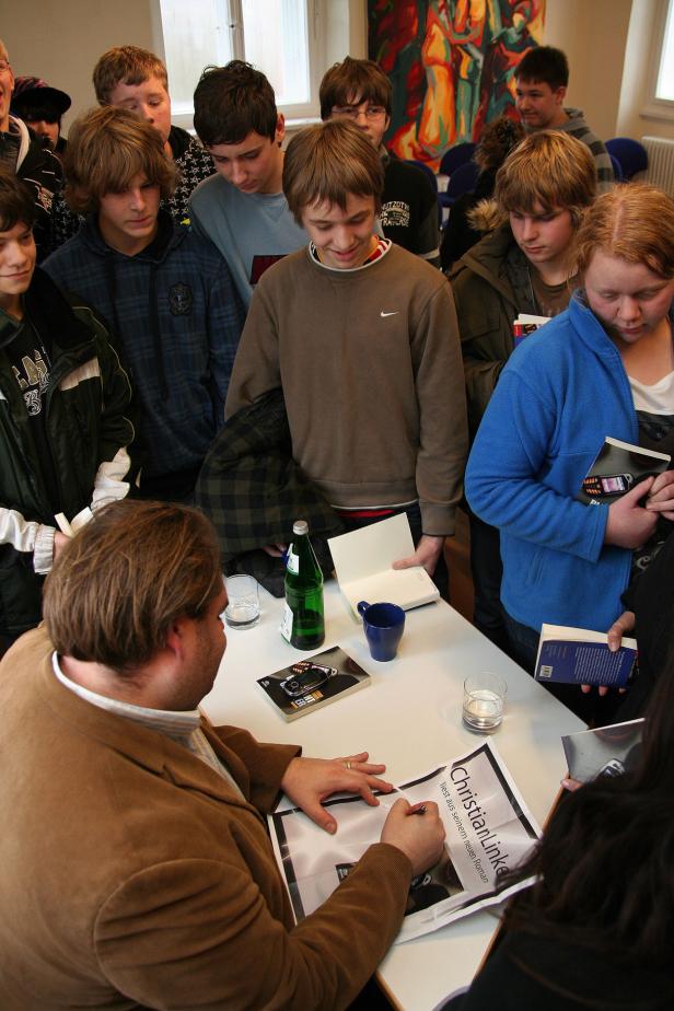 Christian Linker signiert Bücher für eine Gruppe Jugendlicher.