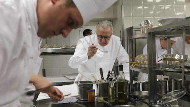 Ein Koch probiert eine Speise in einer professionellen Küche.