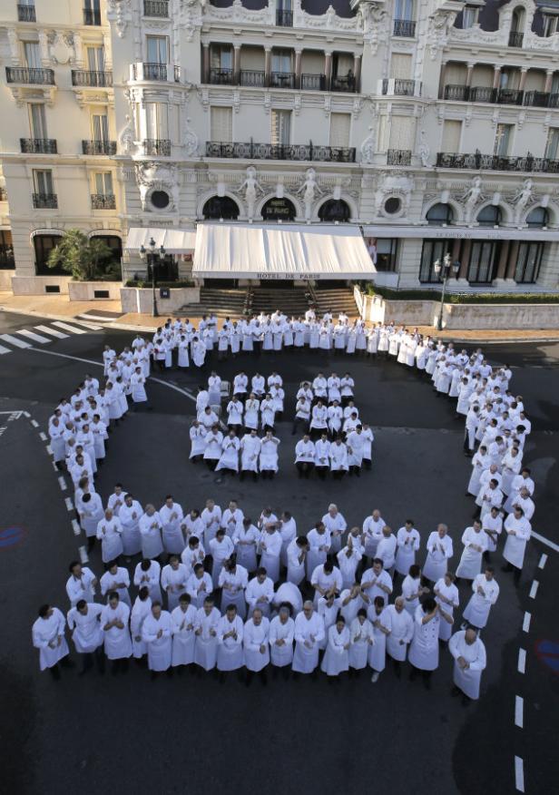 Köche in Kochkleidung formen eine 65 vor dem Hotel de Paris in Monaco.