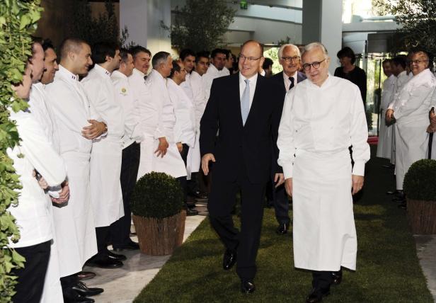 Fürst Albert II. von Monaco geht mit einem Koch durch eine Reihe von Köchen.