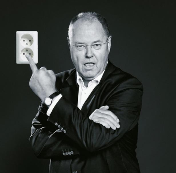 Ein Mann im Anzug zeigt mit dem Finger auf eine Steckdose.