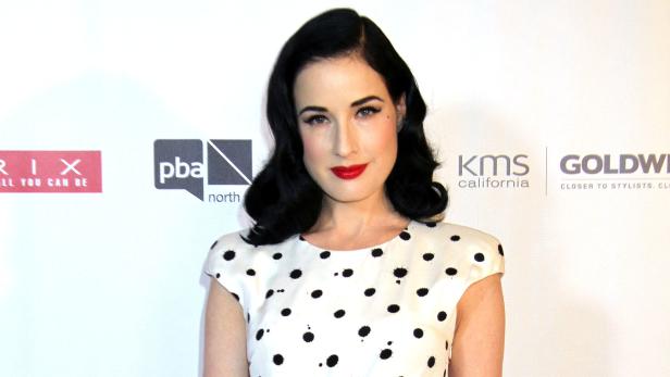 Dita Von Teese mit roten Lippen und einem gepunkteten Kleid.