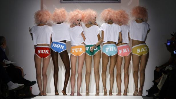 Models präsentieren Unterwäsche mit den Wochentagen auf einem Laufsteg.