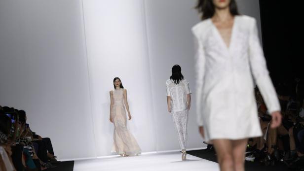 Drei Models präsentieren Kleidung auf einem Laufsteg.