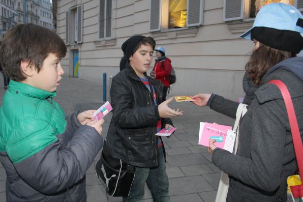 Zwei Jungen erhalten Flyer von einer Frau auf der Straße.