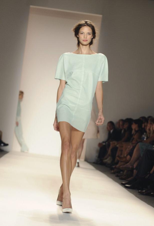 Eine Frau präsentiert ein hellgrünes Minikleid auf einem Laufsteg.