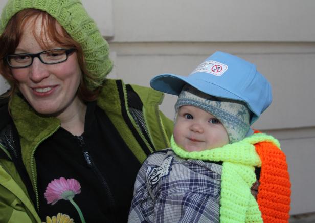 Eine Frau mit einem Baby, das eine blaue Kappe und einen bunten Schal trägt.
