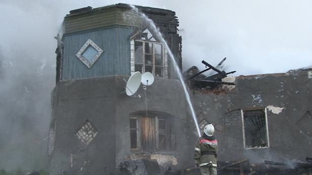 Ein Feuerwehrmann löscht ein brennendes Haus.