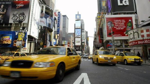 Gelbe Taxis fahren auf einer Straße am Times Square in New York, umgeben von Werbetafeln.