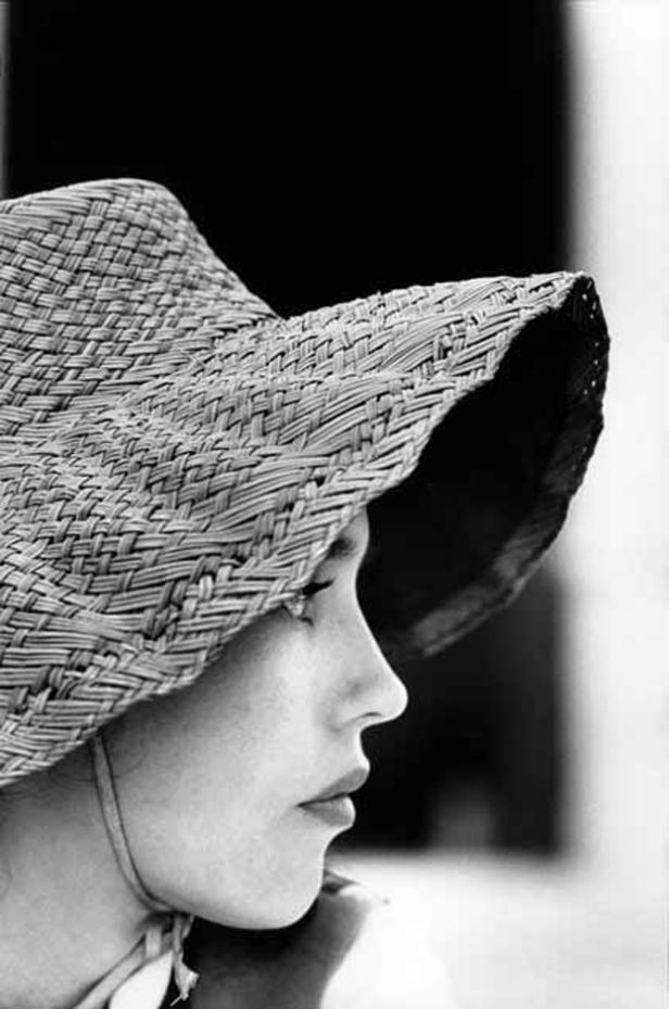 Eine Frau mit einem großen Strohhut, aufgenommen im Profil.