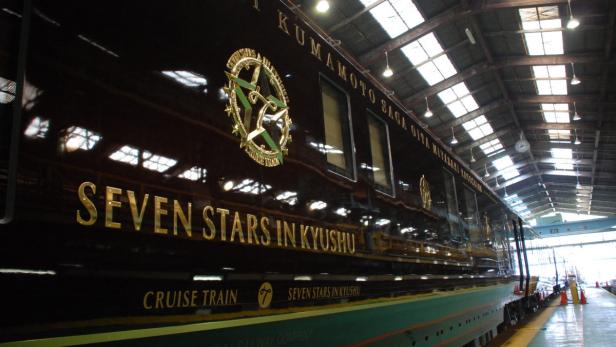 Der Luxuszug „Seven Stars in Kyushu“ steht in einer Halle.