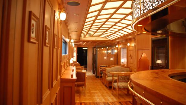 Innenansicht eines luxuriösen Speisewagens mit Holzvertäfelung und eleganten Möbeln.