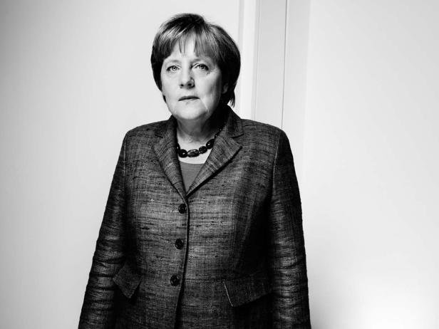 Ein Schwarzweißporträt von Angela Merkel in einem Blazer und einer Halskette.