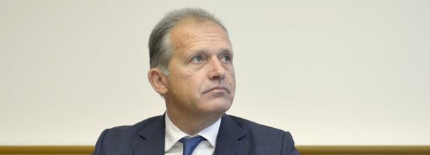 Ein Mann im Anzug blickt aufmerksam zur Seite.