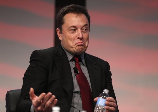 Elon Musk zieht eine Grimasse und hält eine Wasserflasche in der Hand.