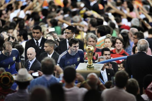 Lionel Messi geht mit dem WM-Pokal durch eine Menschenmenge.