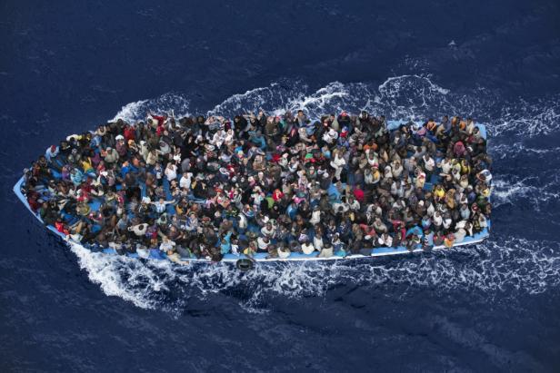 Ein überfülltes Boot mit Menschen auf dem offenen Meer.