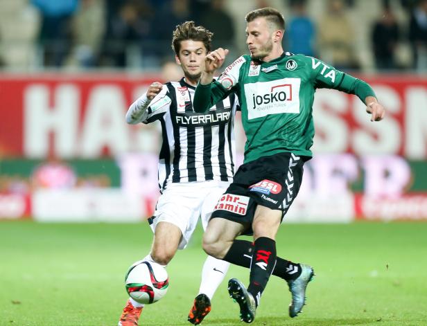 Zwei Fußballspieler kämpfen um den Ball während eines Spiels.