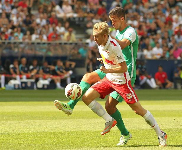 Zwei Fußballspieler kämpfen um den Ball auf dem Rasen.