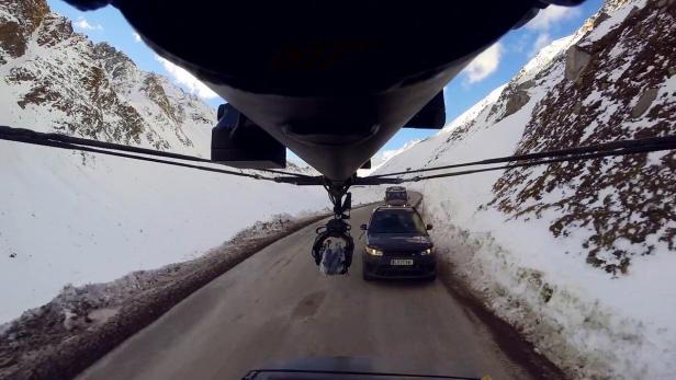 Ein Kamerakran filmt zwei Range Rover auf einer schneebedeckten Bergstraße.