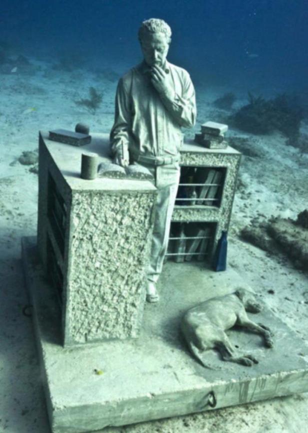 Eine Unterwasser-Skulptur zeigt einen Mann am Schreibtisch und einen liegenden Hund.