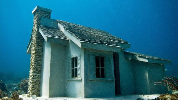 Ein kleines Haus mit Schornstein steht unter Wasser.