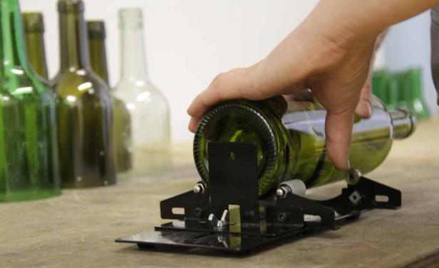 Eine grüne Glasflasche wird mit einem Glasschneider bearbeitet.