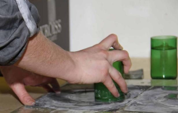 Eine Person schleift Glas mit einem grünen Glaszylinder.