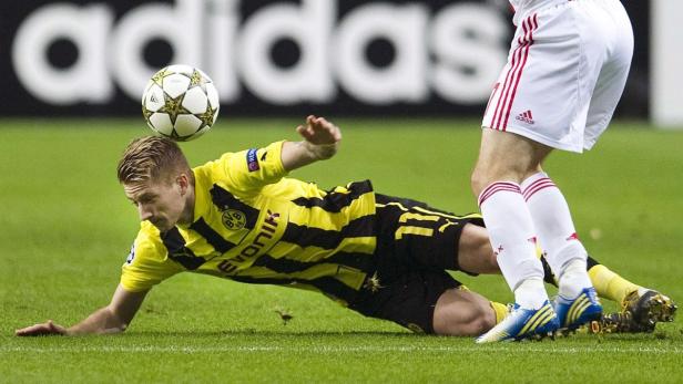 Ein Fußballspieler köpft den Ball, während ein anderer Spieler versucht, ihn zu Fall zu bringen.