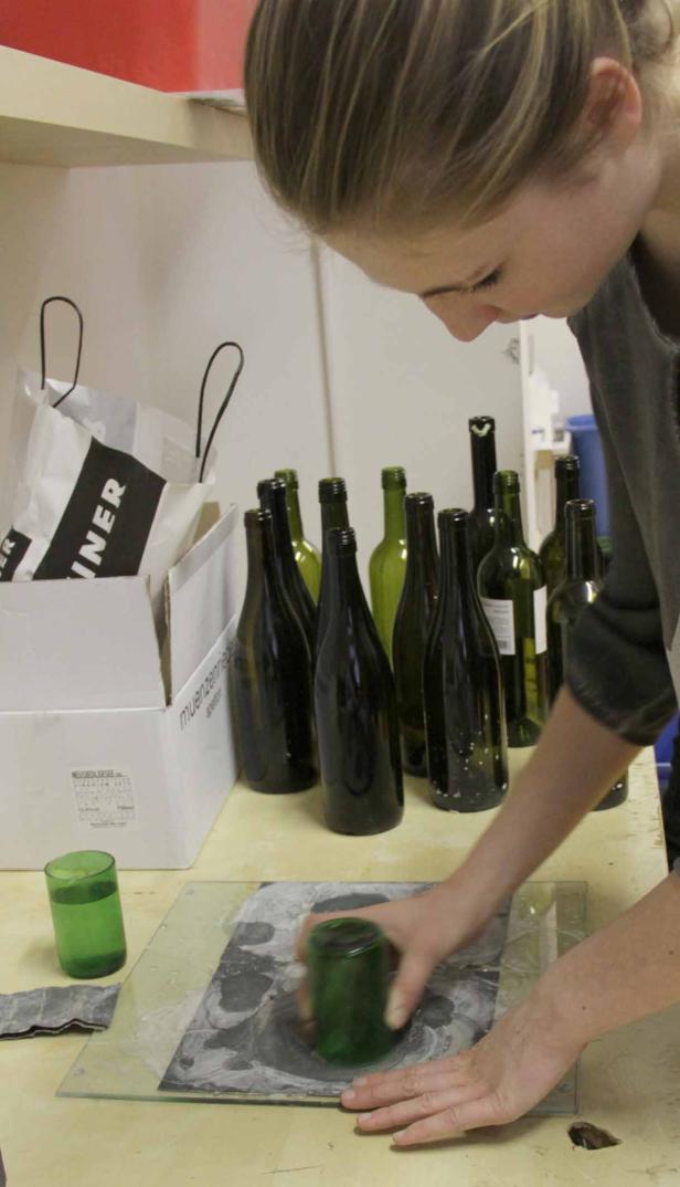 Eine Frau schleift ein Glas mit einem anderen Glas auf einer Glasplatte.