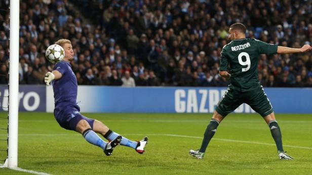 Karim Benzema schießt den Ball, während der Torwart versucht, ihn abzuwehren.
