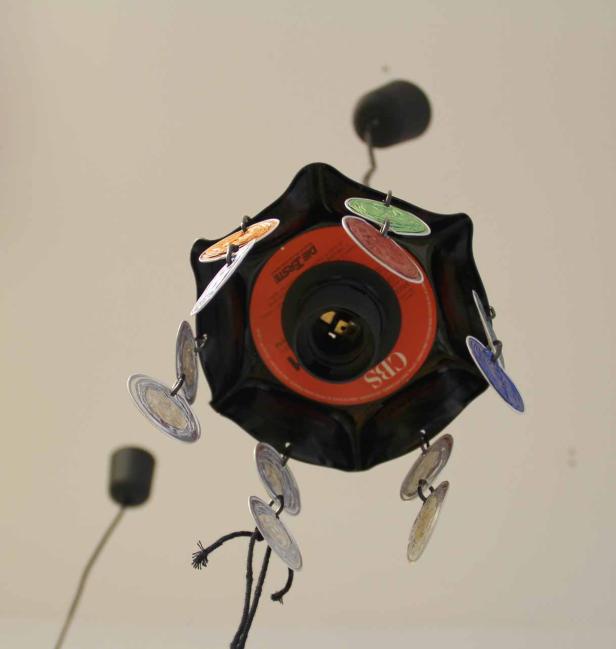 Eine Lampe, die aus Schallplatten und kleinen Vinylscheiben gefertigt ist.