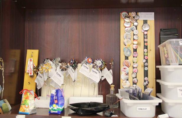 Ein Regal mit verschiedenen Artikeln, darunter Caritas-Blumen und Buttons.