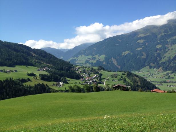 Blick auf ein grünes Tal mit einem Dorf in den Bergen.