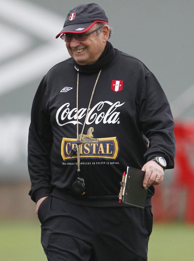 Ein lächelnder Mann in Sportkleidung mit Coca-Cola- und Cristal-Logos hält ein Klemmbrett.