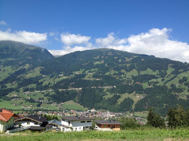 Blick auf ein Dorf in den österreichischen Alpen unter blauem Himmel.