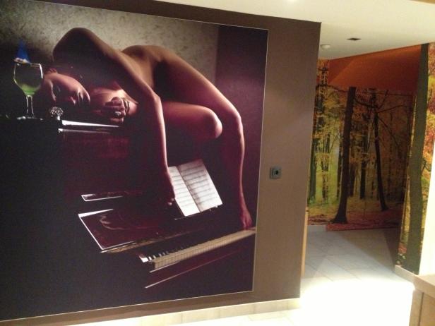 Ein Akt liegt auf einem Klavier neben einem Cocktail mit Notenblatt.