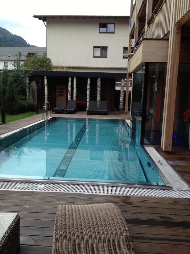 Ein Schwimmbad im Freien mit Liegestühlen und Birkenstämmen als Dekoration.