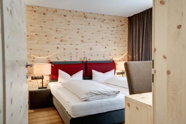 Einladendes Schlafzimmer mit Holzwänden und einem Doppelbett mit roten Kopfteilen.