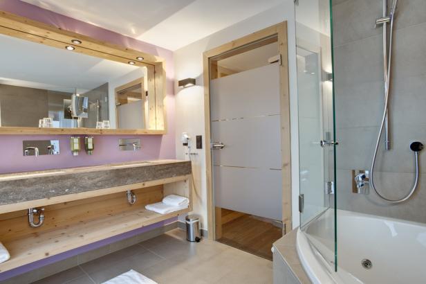 Ein Badezimmer mit Doppelwaschbecken, Spiegel und einer Dusche mit Badewanne.